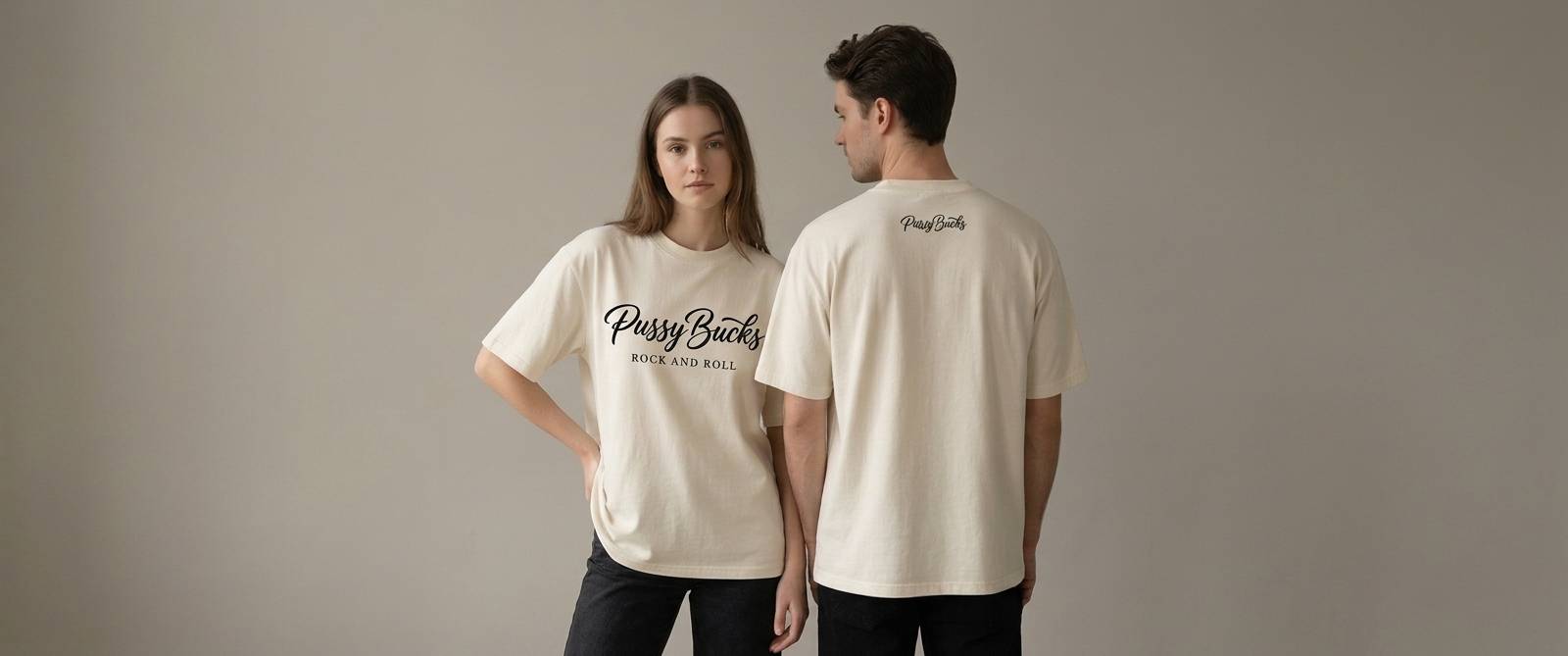 A couple in desert sand PussyBucks tees — the full lockup across the front, the script across the upper back